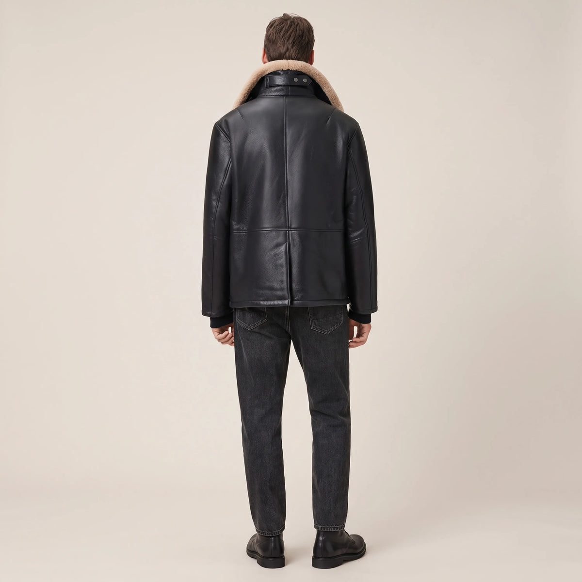 Black shearling leather coat with sand collar worn with dark jeans, full-length view