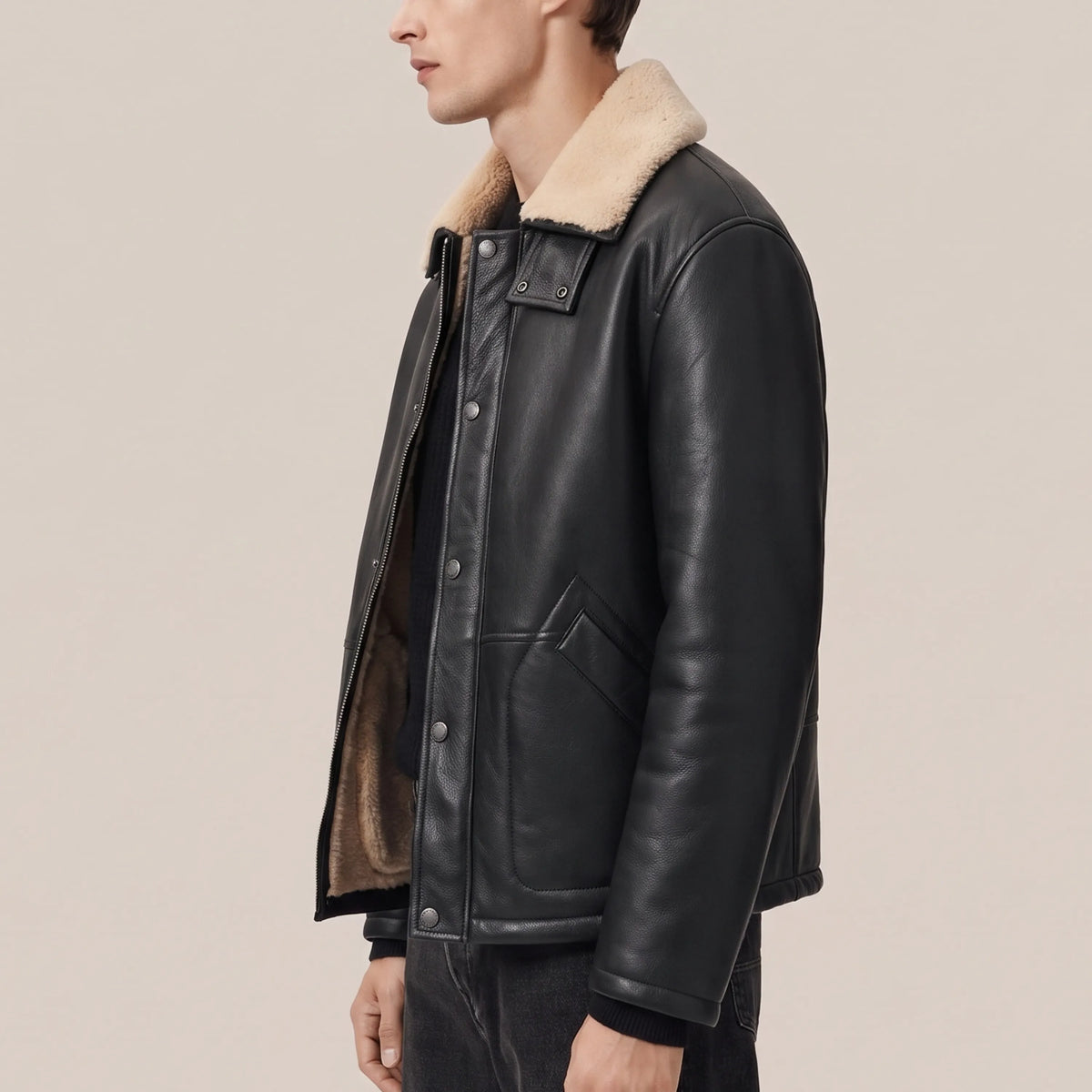 Three-quarter view of men’s black leather coat with sand shearling collar